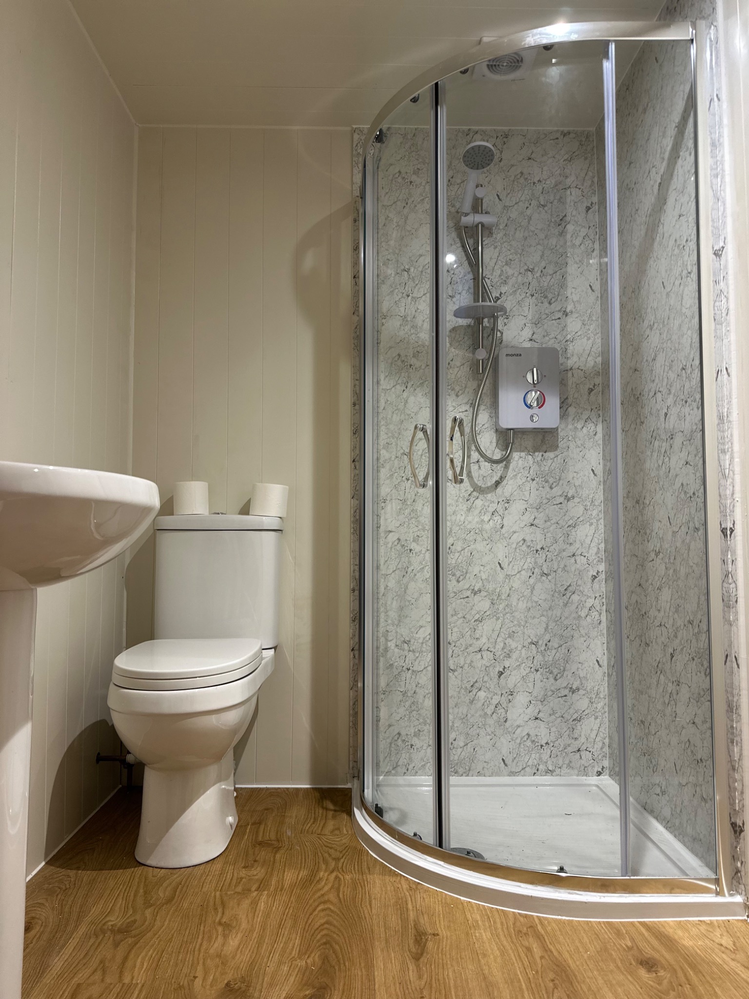Completed bathroom with shower enclosure and timber-effect flooring