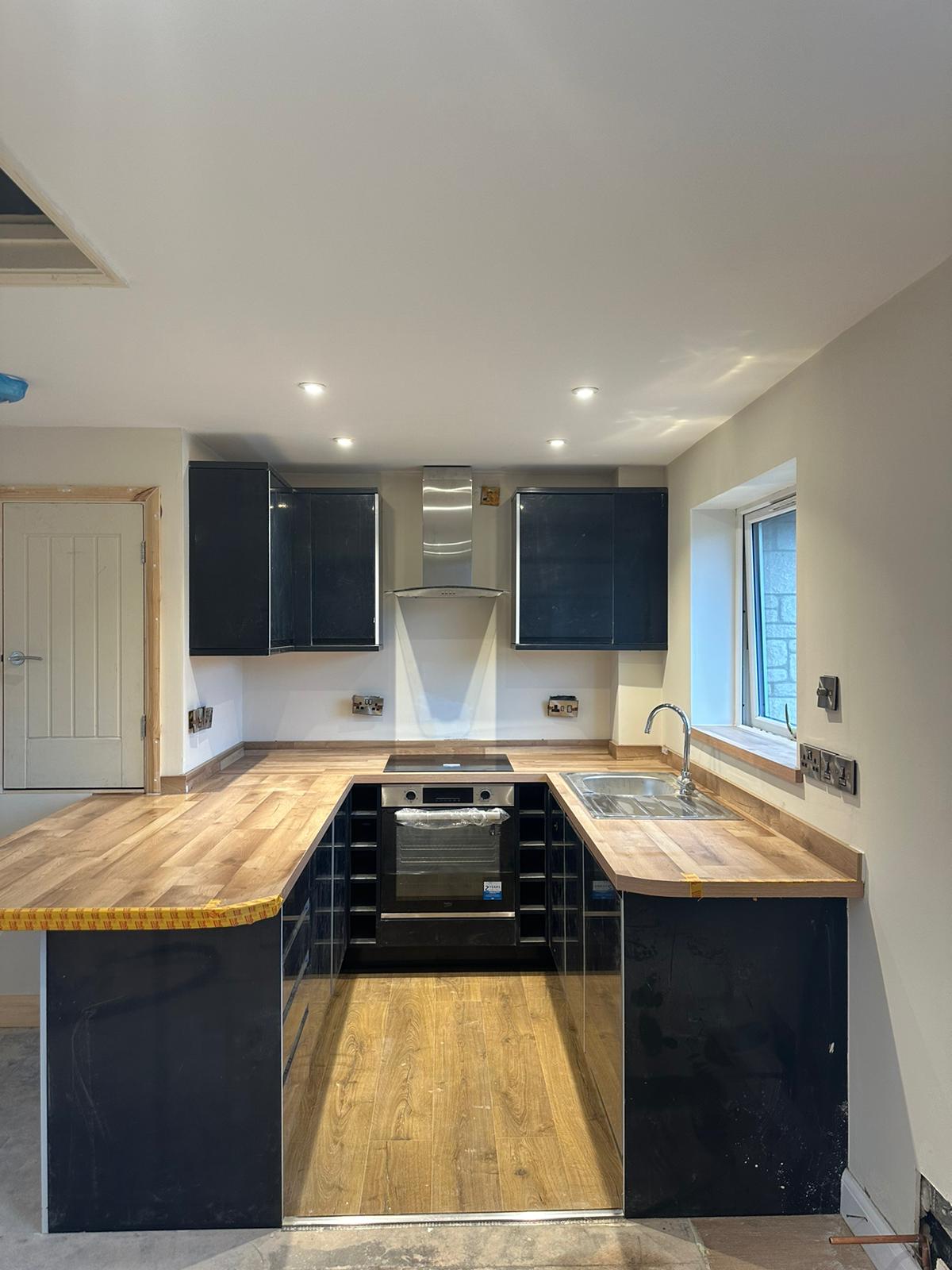 Completed fitted kitchen with timber worktops and dark cabinetry